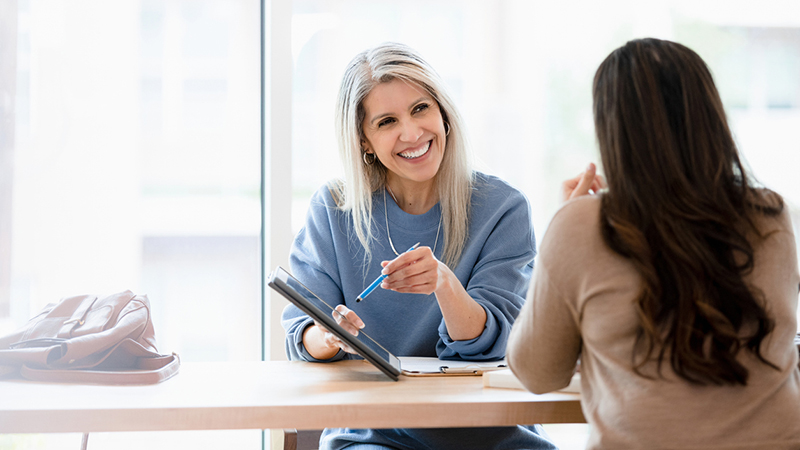 A women showing another person something on a tablet