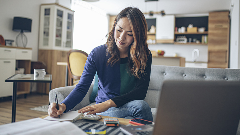 Woman sitting on a couch working with a calculator